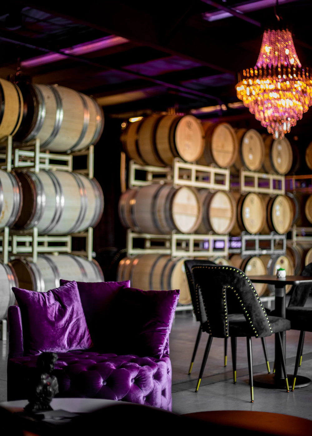 VIP lounge with wine barrels, purple couch, and chandelier.